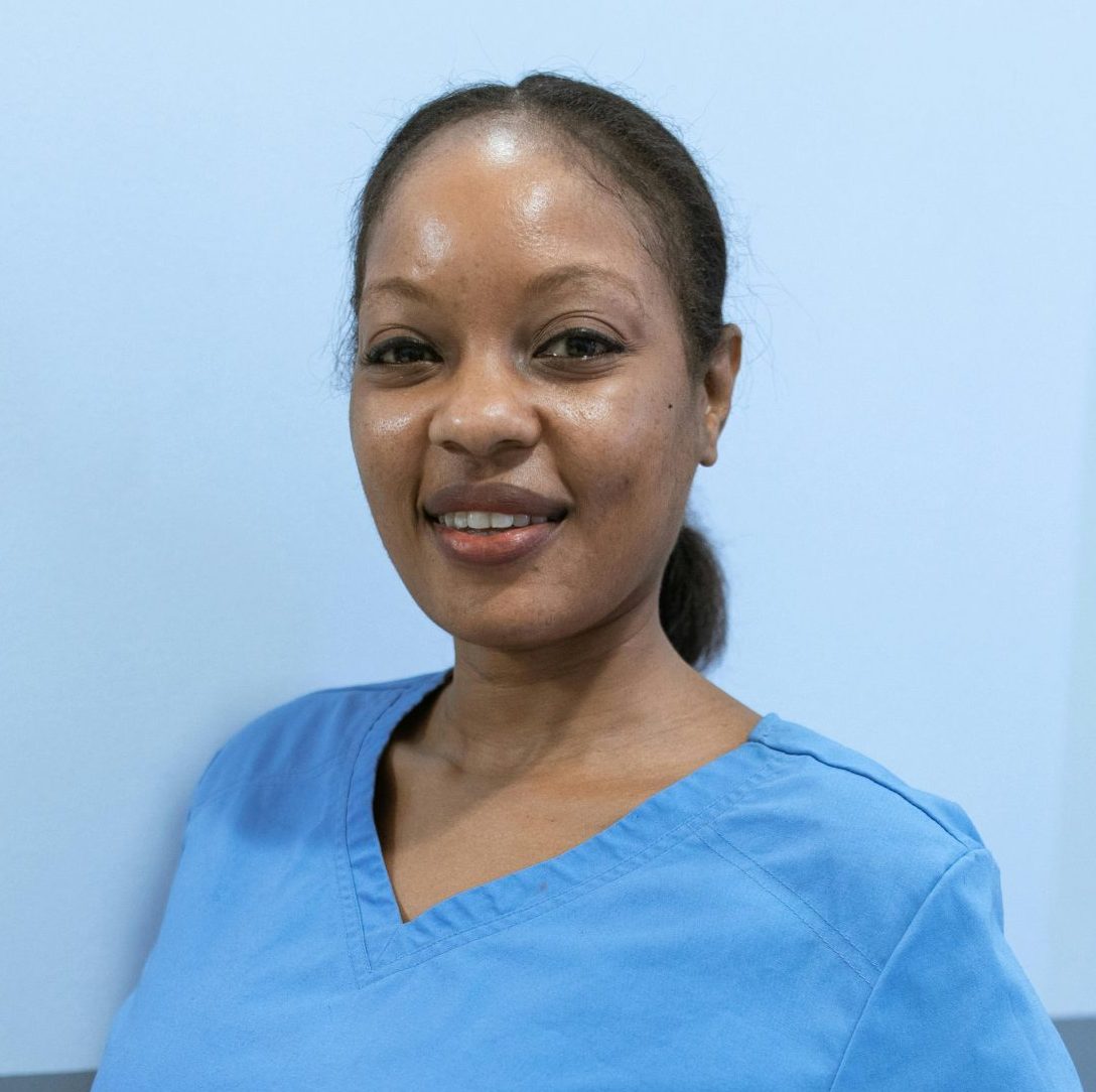 African American nurse smiling confidently indoors, wearing blue scrubs.