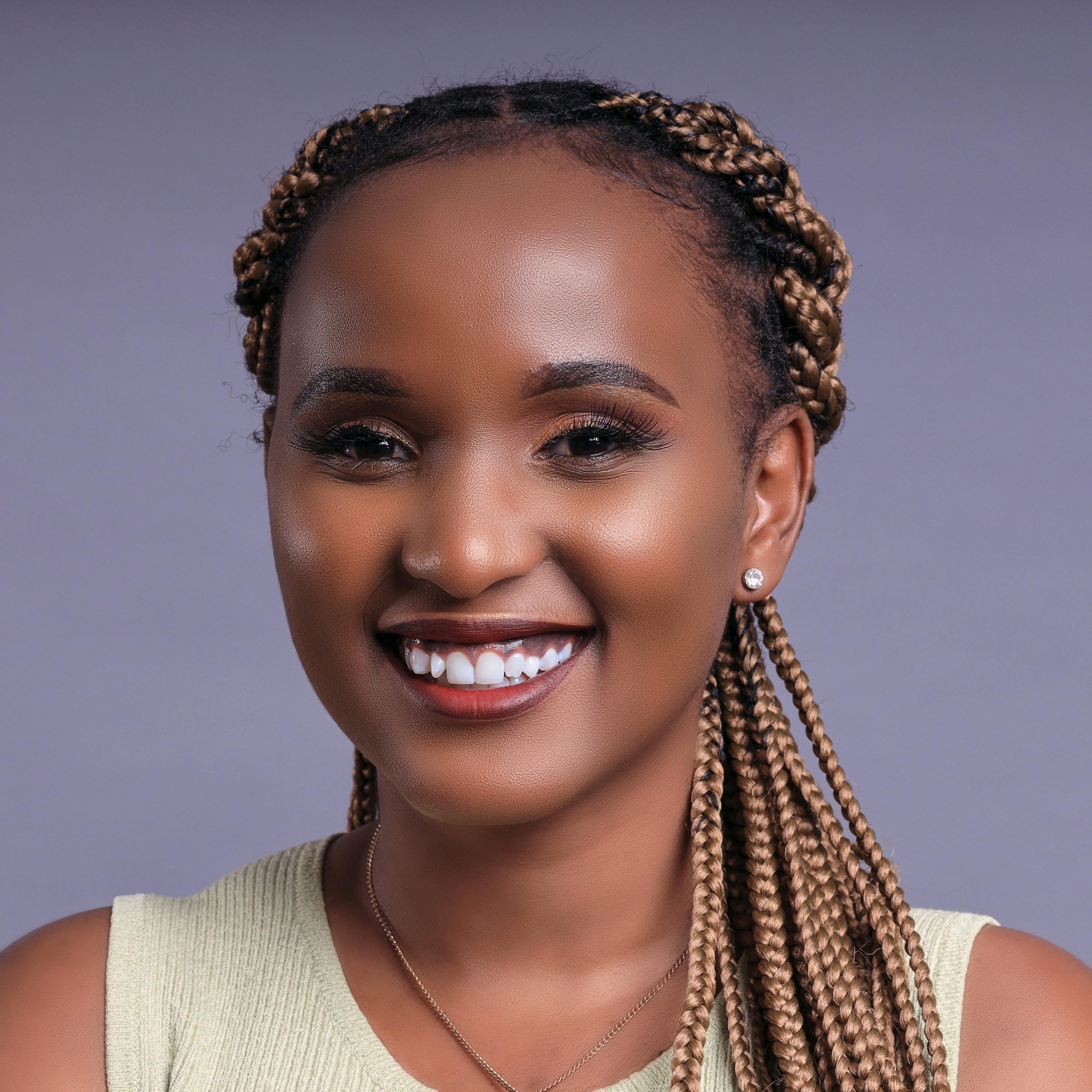 Close-up portrait of a smiling woman with braided hair, exuding happiness.